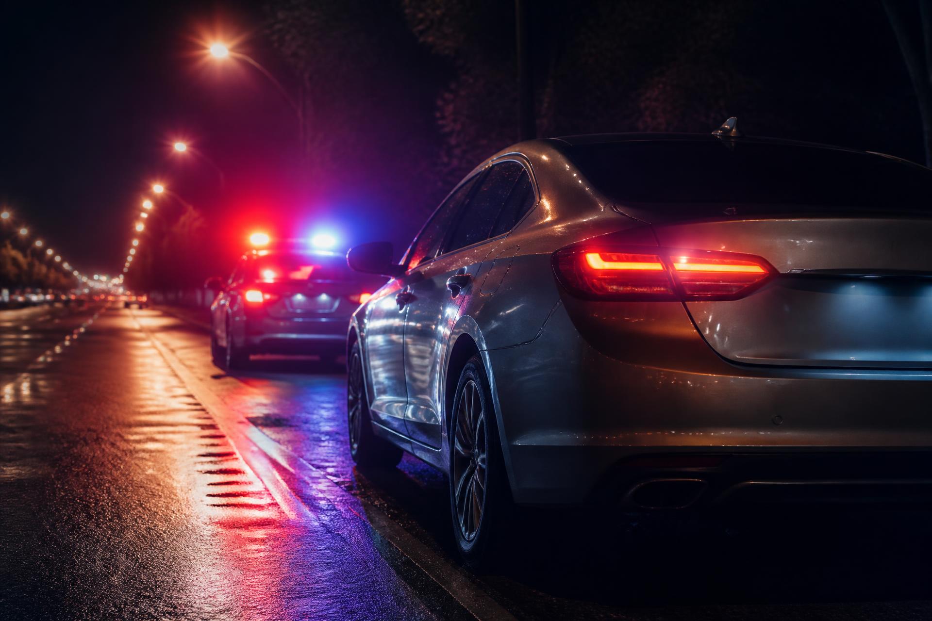 Car pulled over at night with police lights behind it